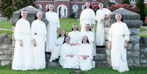 group of eleven Dominican Sisters standing in a group on the front steps of St. Cecilia Motherhouse